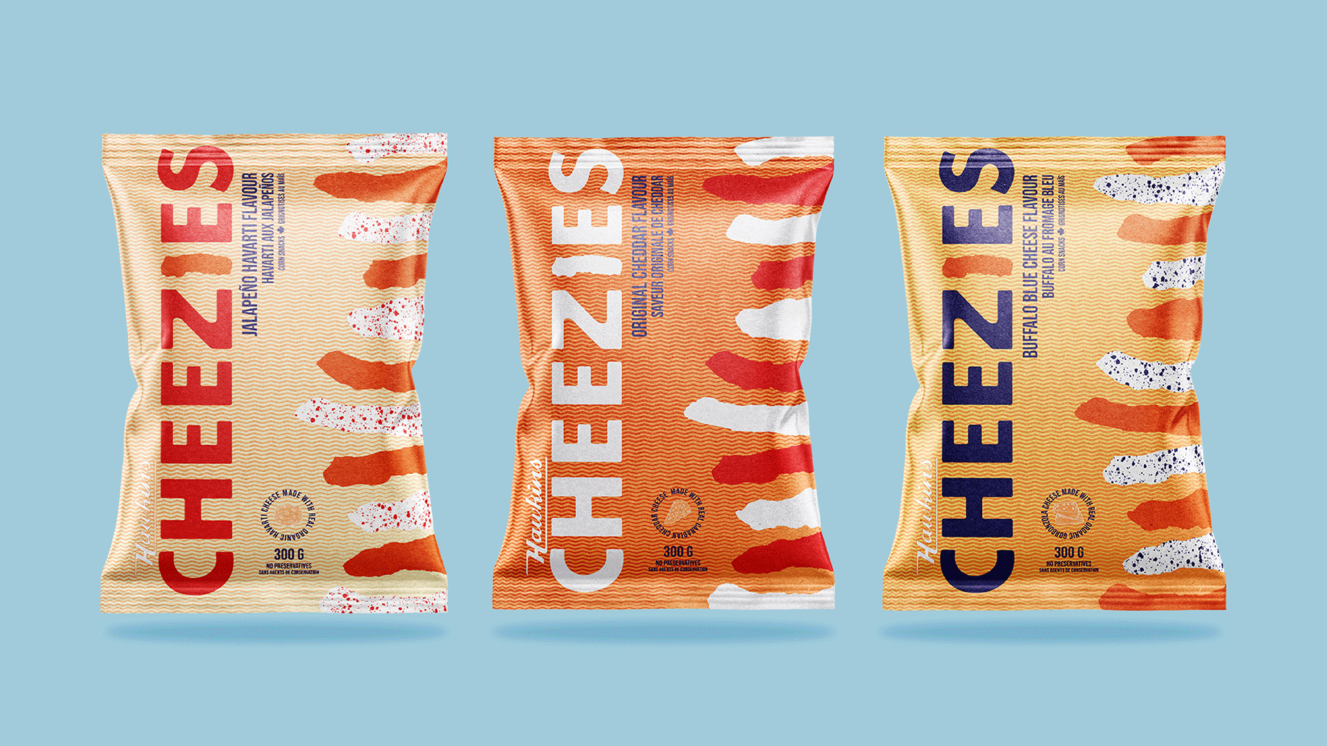 Three small foil bags of Cheezies sit on a light blue background. The bags primarily cream, orange and yellow with the word Cheezie written down the left side and illustrations of Cheezies on the right side.