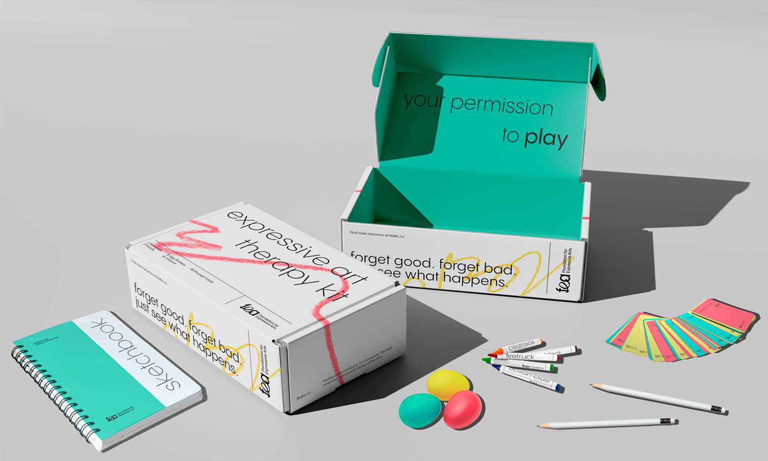 An image of an expressive art therapy kit including a sketchbook, two boxes, 3 egg shakers, crayons, pencils, and cards. The designs use white, teal, red, and yellow, featuring clean sans-serif typography and expressive crayon scribbles.